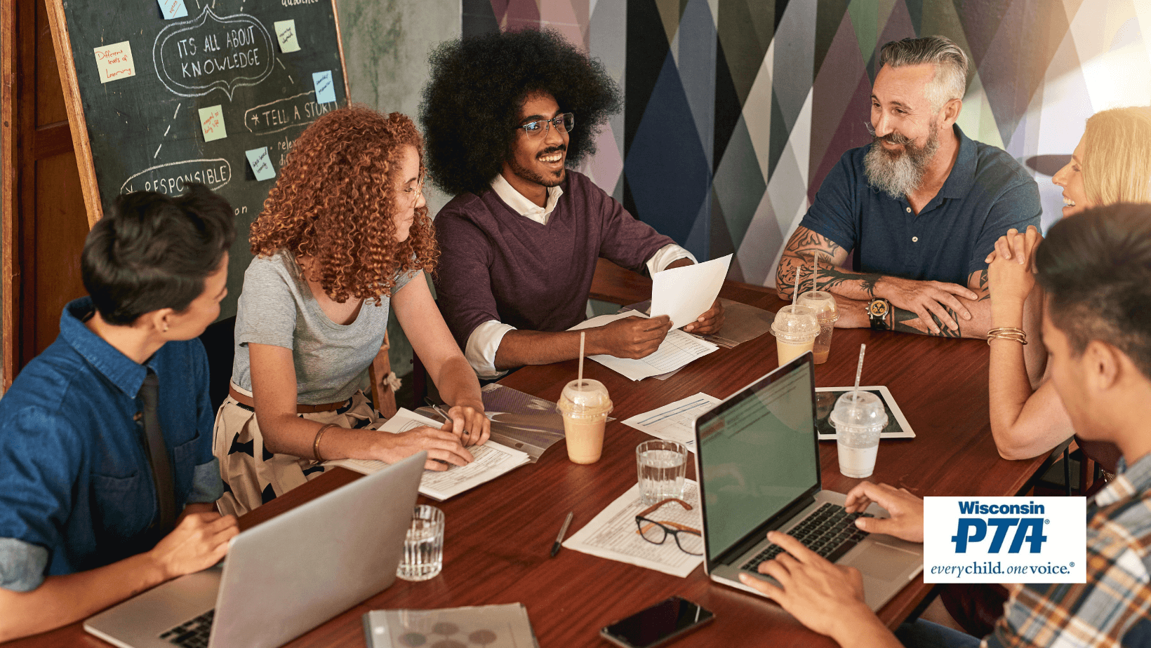 A group of people sitting around a table with laptops.